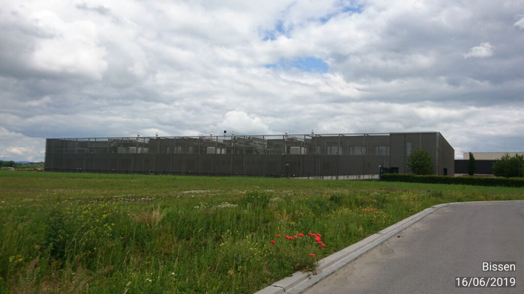 Ein Foto des Rechenzentrums Lux-Connect in Bissen. Es handelt sich um einen großen grauen Kasten auf einer grünen Wiese.