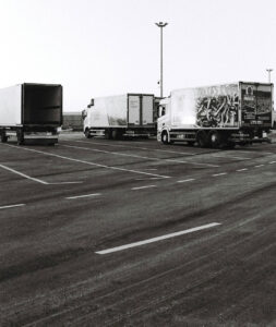Drei Lastkraftwagen stehen auf ansonsten leerem Parkplatz, einer hat die Türen aufgeschlagen und ist leer.