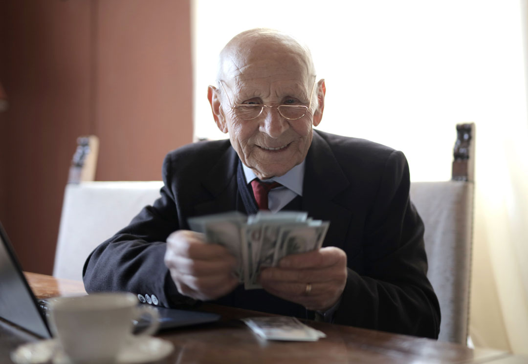 un viel homme avec une liasse de billets de banque
