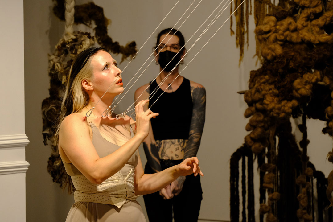 Die Künstlerin Françoise zupft bei ihrer Performance an den Ketten, die durch Piercings direkt mit ihrem Körper verbunden sind.