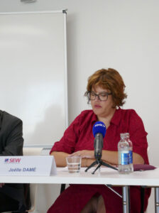 Une femme assise à une table parle dans un micro